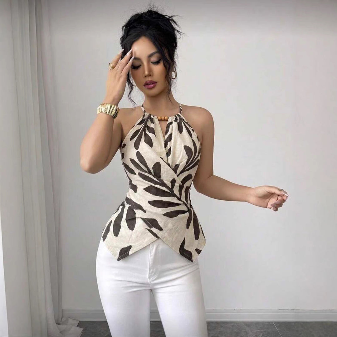 Beige sleeveless top with black leaf print, halter neckline and tie-front waist detail
