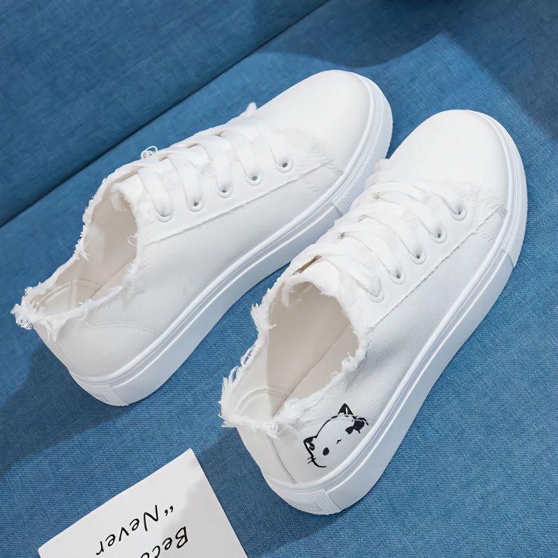 Women’s canvas sneakers, white with lace-up front and low-profile rubber sole.