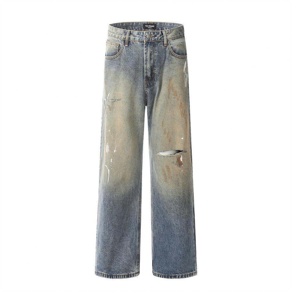 Men's ripped jeans in faded blue denim with mud-dye stains on thighs and knees