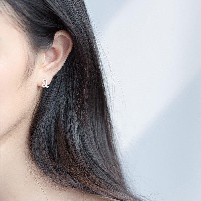 Zodiac wishing earrings, small silver-tone charm with constellation details in ear close-up