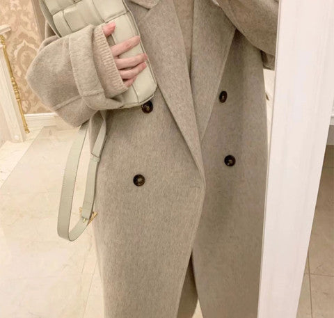 Beige overcoat detail: wide lapels, long sleeves, and dark button closure