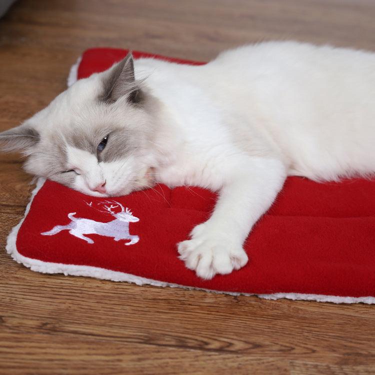 Christmas pet mat with red fabric, white trim, and reindeer design; cat resting on top.