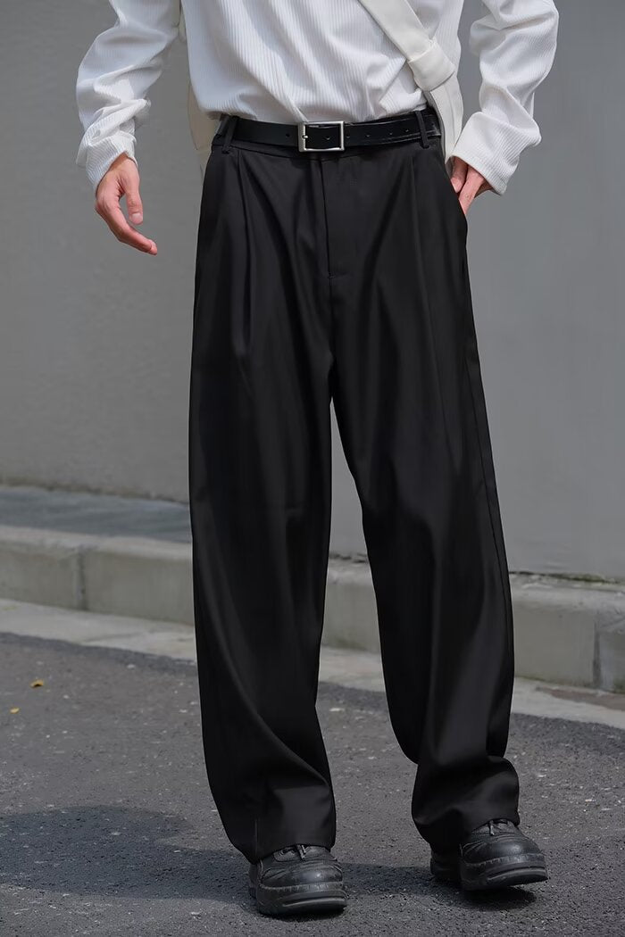 Black loose straight-leg pants with waistband belt, pleats, and cuffed hem.