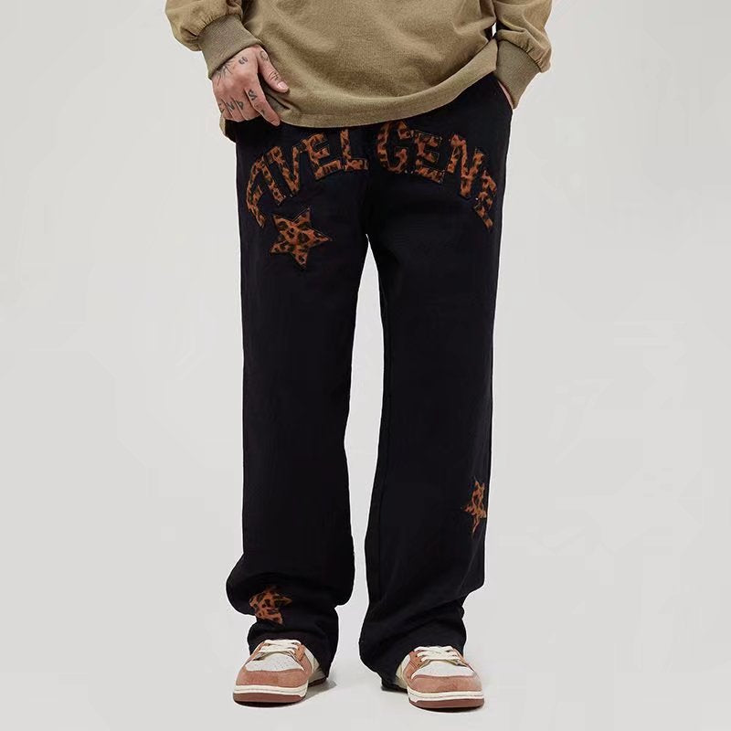 Black casual workwear pants with brown embroidered lettering and star details