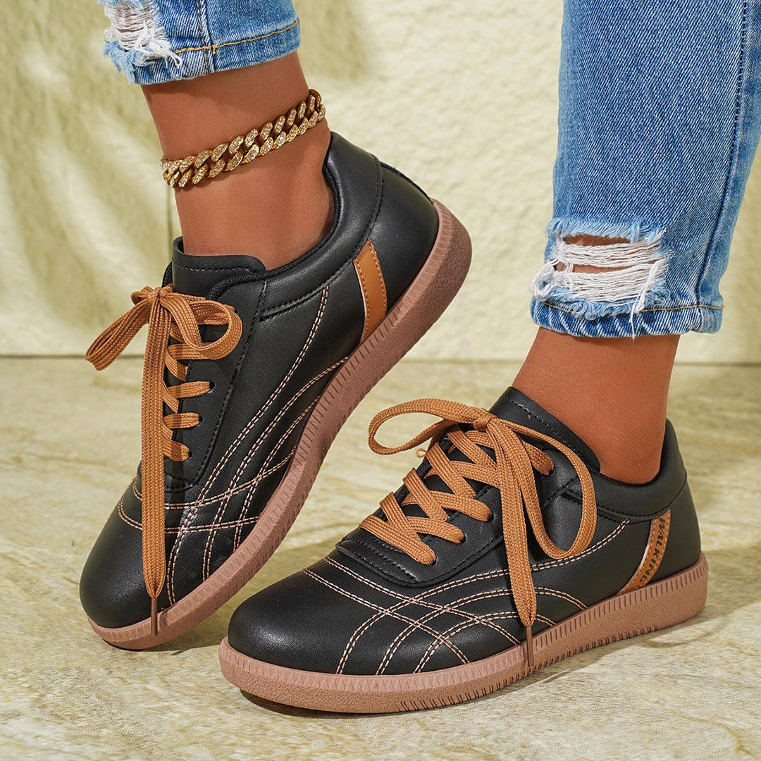 Black lace-up sneakers with tan laces and thick tan rubber sole, round toe