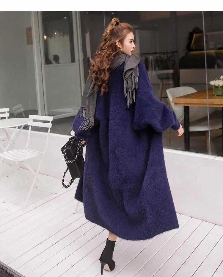 Purple long fuzzy sweater coat with wide sleeves and fringe scarf detail.