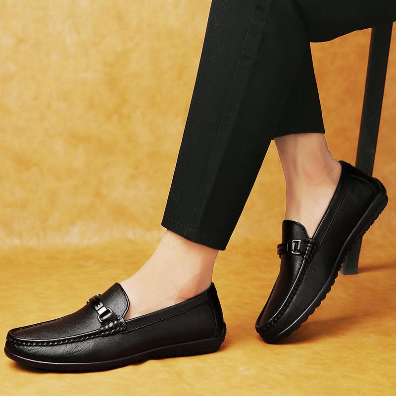 Black leather loafer with metal buckle strap, worn with dark pants