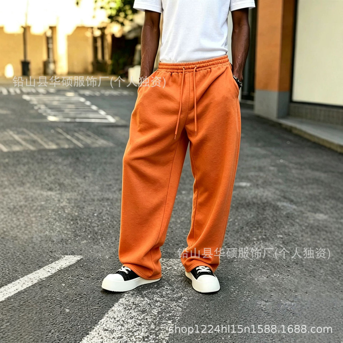 Orange elastic-waist sweatpants with drawstring and loose straight legs with ankle cuffs.