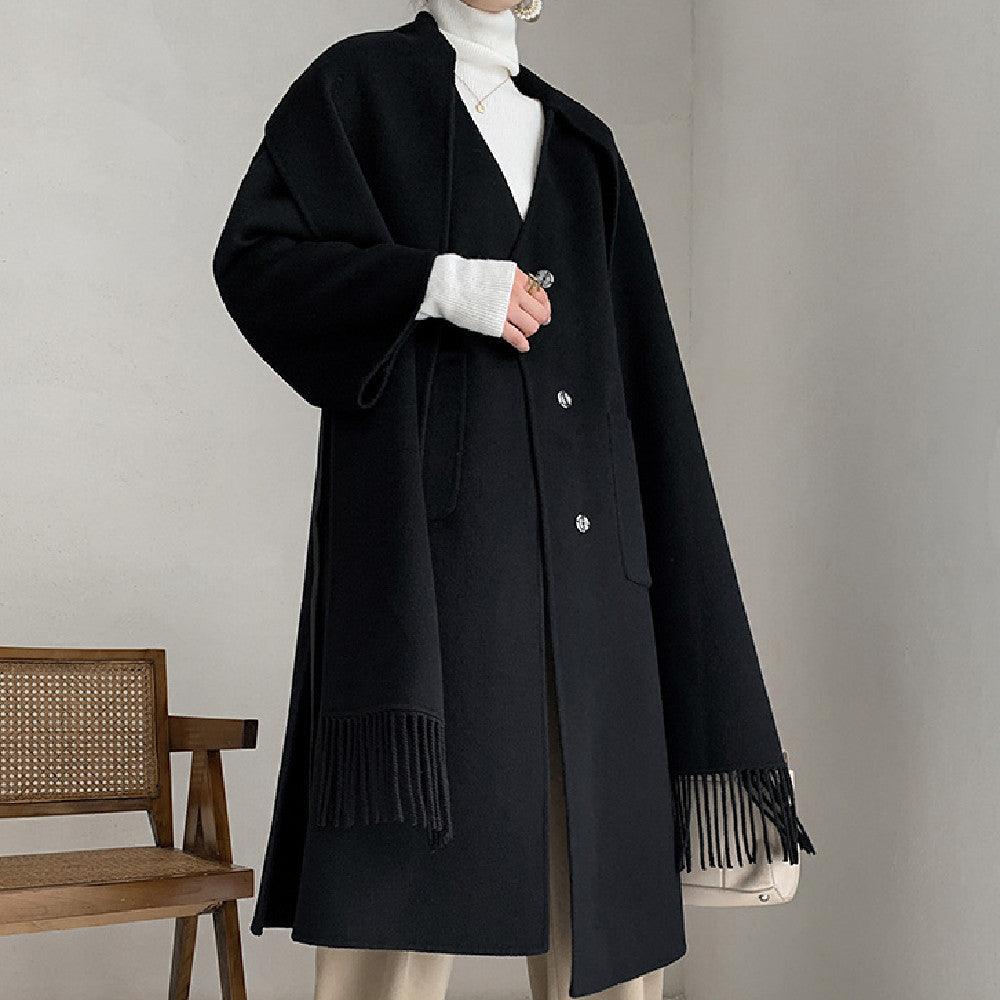 Black long wool coat with hood, button front, tie belt, and fringe scarf hem