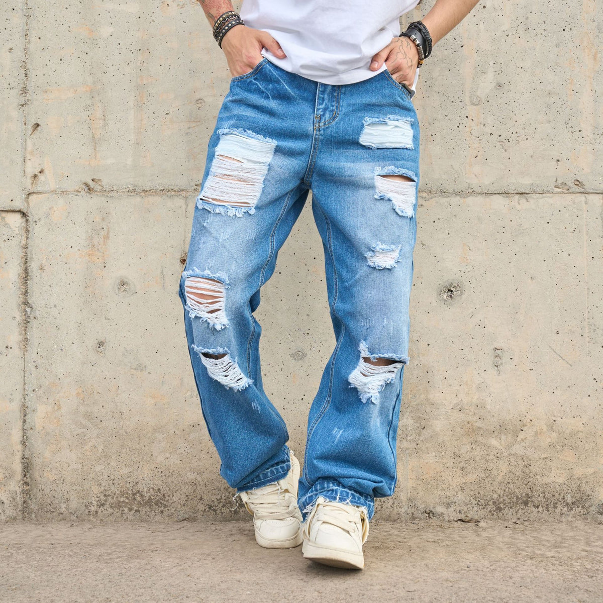 Relaxed blue denim jeans with big distressed panels and frayed knee rips