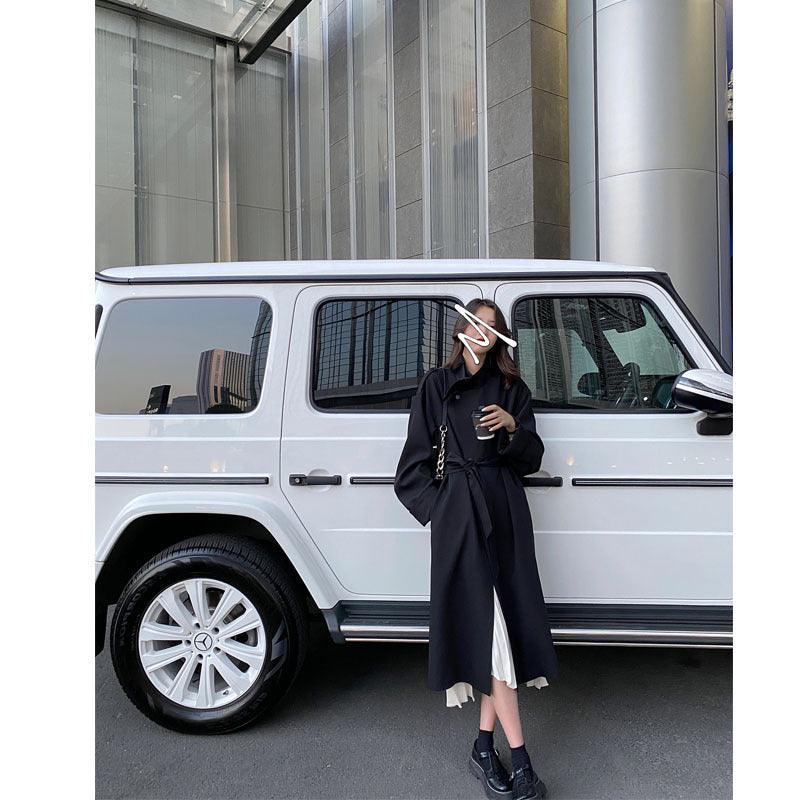 Women’s dark trench coat with belt, long sleeves, button front, mid-calf length.