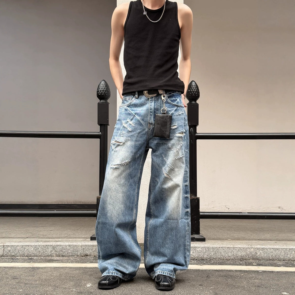 Light blue ripped men's wide-leg denim jeans with heavy distressing and dark patch pocket