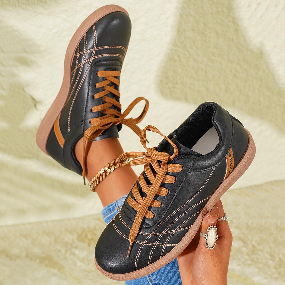 Black lace-up sneakers with tan laces, thick tan sole, cushioned collar