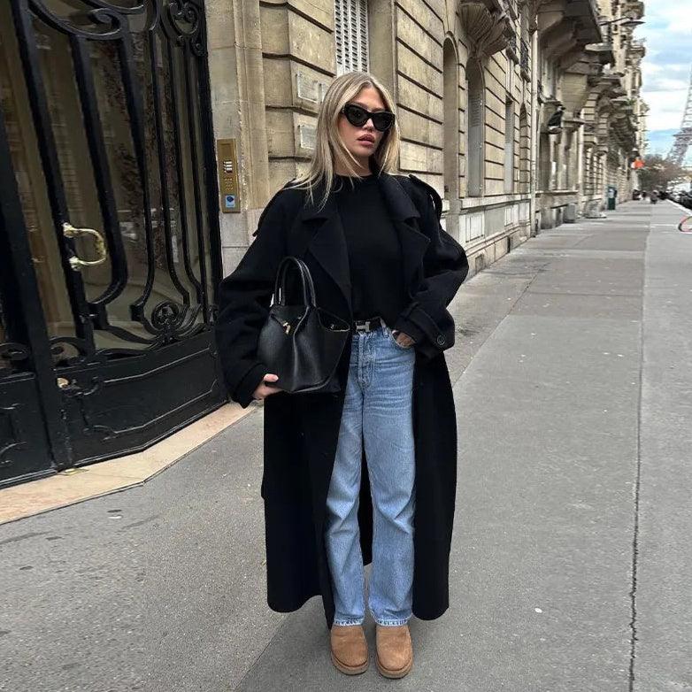 Women’s black trench coat with wide lapels, long length, and tie belt