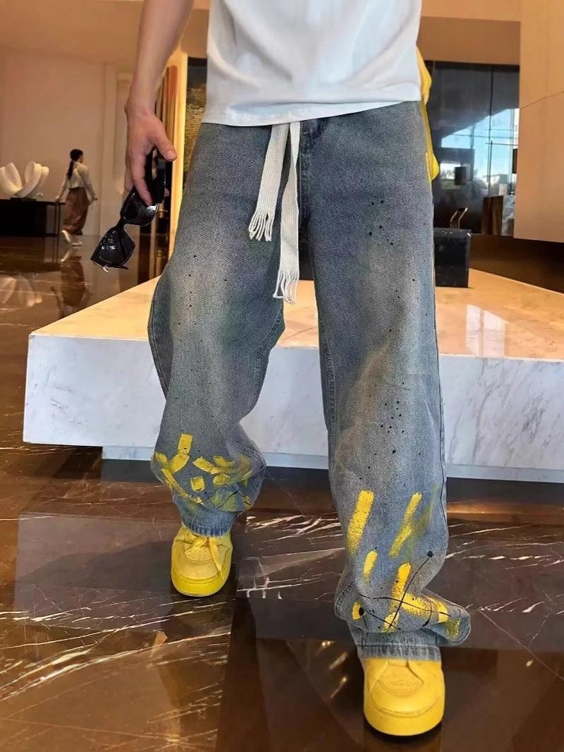 Men's casual light-wash jeans with yellow ink splatter; straight-leg fit and waist ties