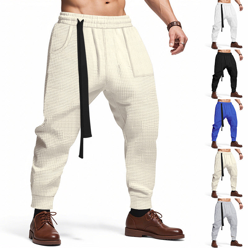 Cream waffle track pants with elastic waistband and black drawstring, tapered legs
