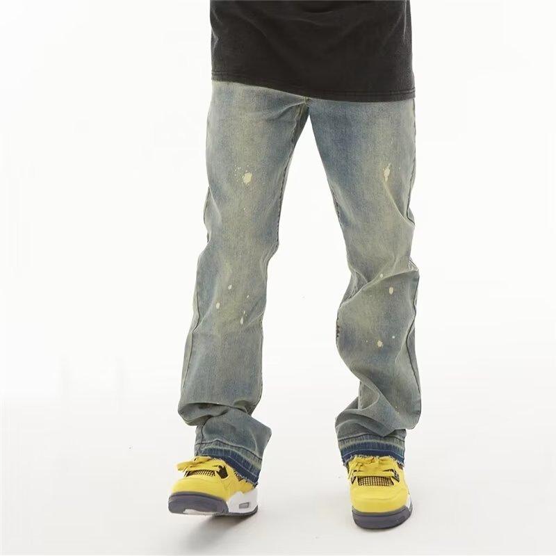 Distressed blue denim pants with light speckle spots and cuffed straight hems.