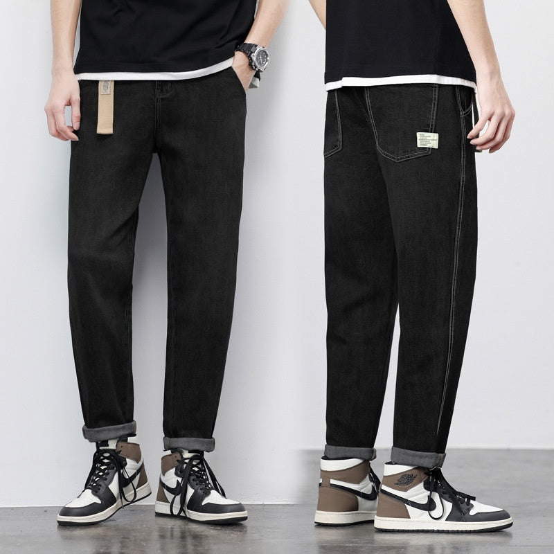 Black thin denim jeans, loose straight-leg fit, tan label on front pocket, cuffed hem
