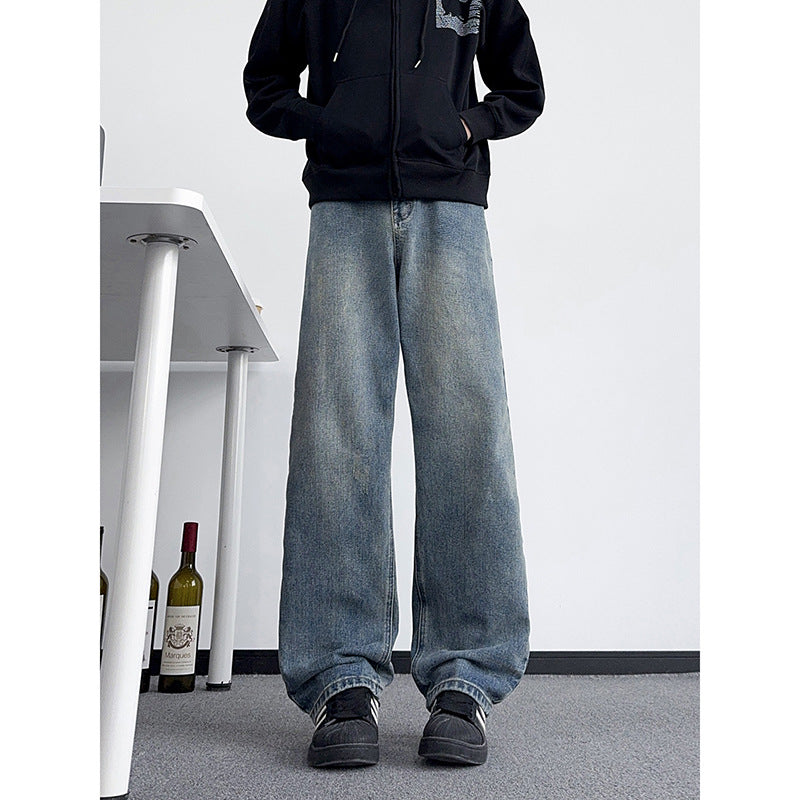 Men's medium blue distressed jeans with relaxed wide legs and worn hem finish