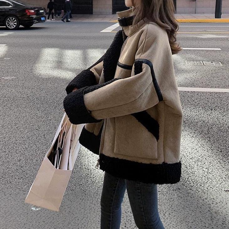 Women’s shearling-style coat in cream with wide black fur hem and cuffs, zip front.