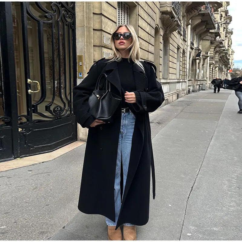 Women’s black trench coat front view with lapels, long sleeves, and tie belt