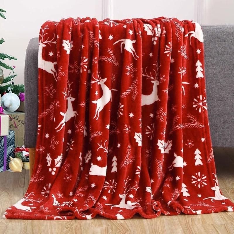 Christmas blanket with red base and white reindeer, stars, and snowflake pattern
