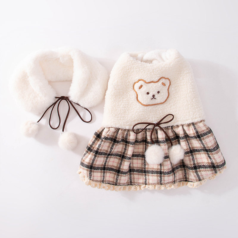 Cream plush dog dress with bear face patch, plaid skirt, and dangling pom-pom cuffs