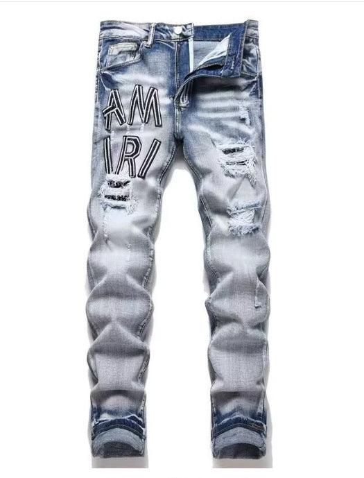 Light blue slim jeans with black “AM IR” text print and distressed rips