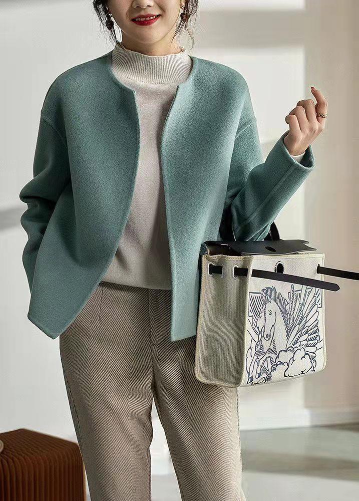 Teal round-neck short cardigan worn over a top with long sleeves