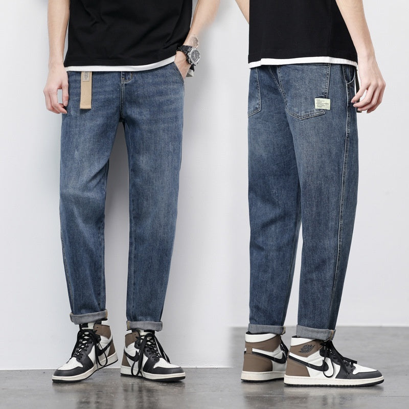 Light blue loose straight-leg denim jeans, tan patch on pocket, cuffed hem