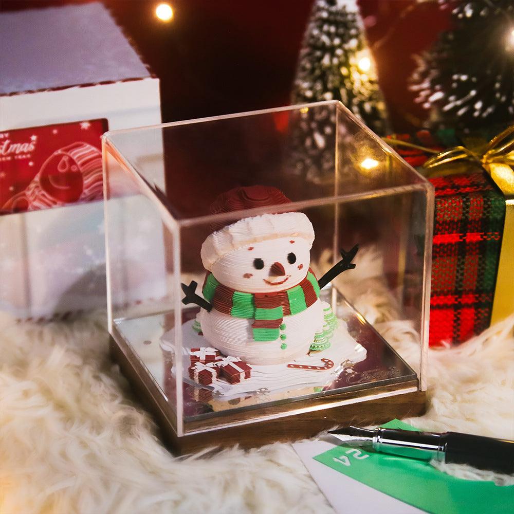 3D weekly calendar paper with snowman figurine on a red plaid scene, in clear display case