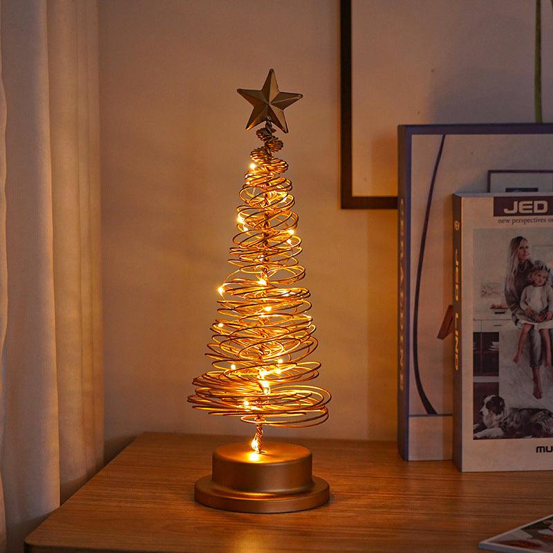 Gold spiral tree desk lamp with star topper, glowing warm coil on a round gold base.