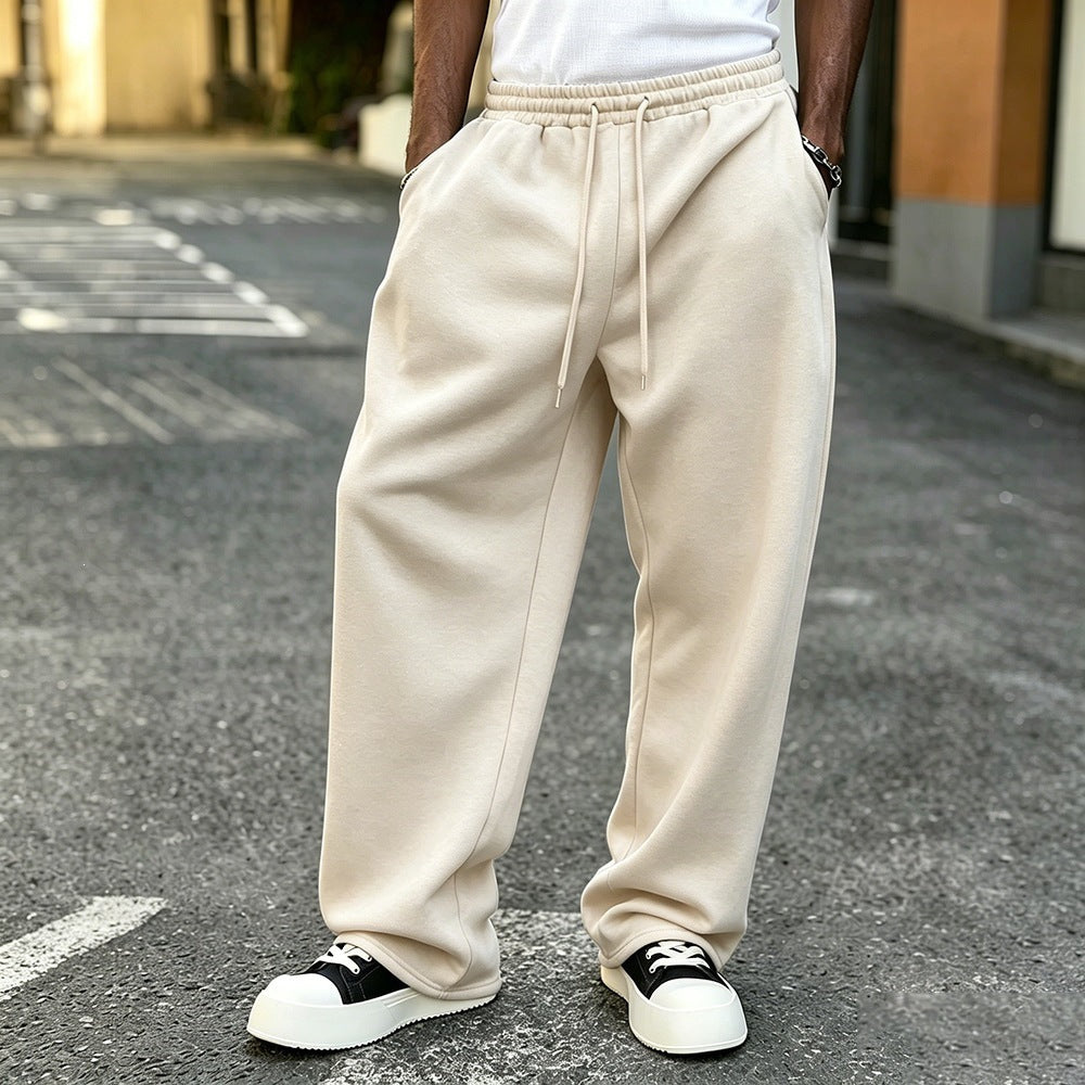 Cream elastic-waist sweatpants with drawstring, loose straight leg cuffs at ankles.