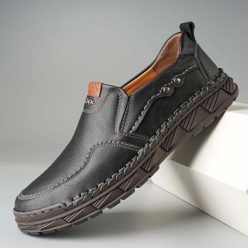 Black slip-on casual shoes with pull tab, contrast stitching, and textured sole tread