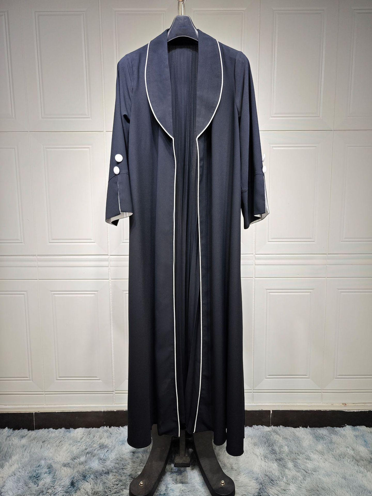 Long cardigan dress in dark blue with open front, V lapels, and white piping trim.