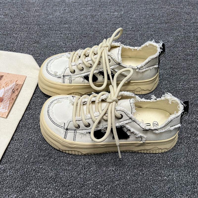 White platform sneakers with lace-up front, distressed openings, beige sole