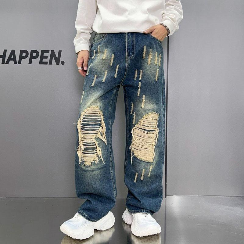 Blue washed wide-leg jeans with large ripped knee patches and gold paint-like marks