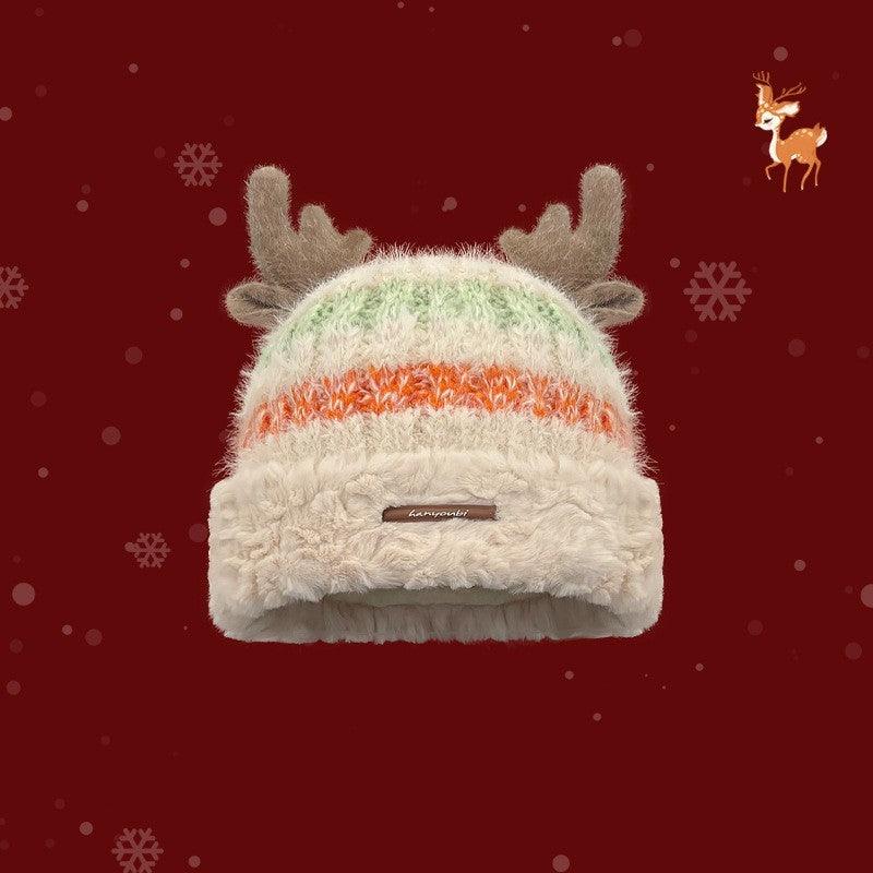 Cream knit winter beanie with beige deer antlers and multicolor striped band, brand label.