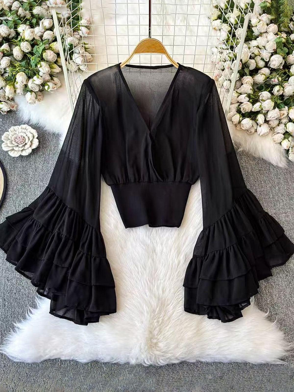 Black deep V-neck cropped top with long flared sleeves and tiered ruffle cuffs