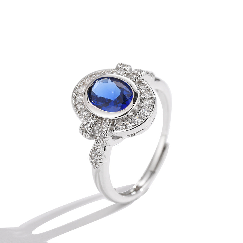 Silver-tone oval blue gemstone ring with prong-set halo and detailed split band