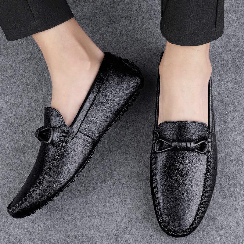 Pair of men's black slip-on loafers with buckle detail and textured outsole