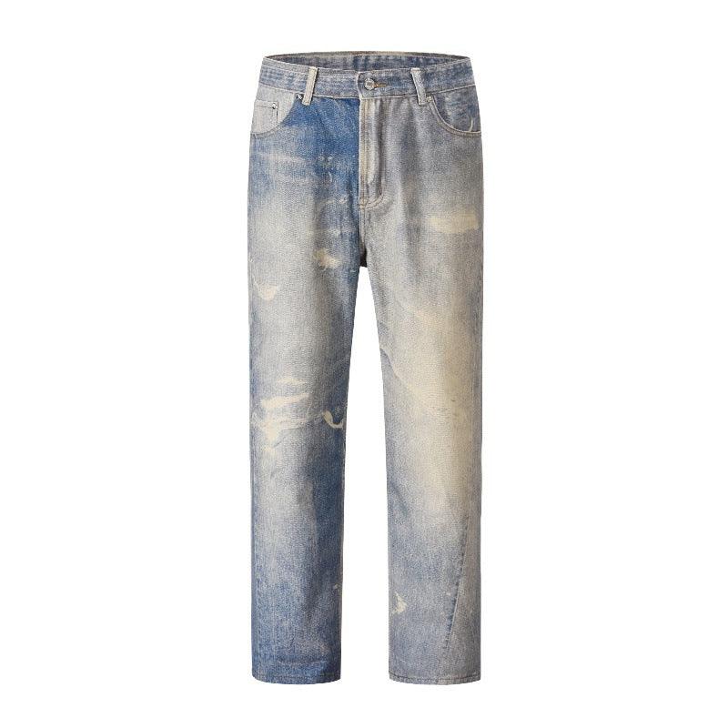 Blue-gray washed distressed denim trousers with multiple faded areas and front fly