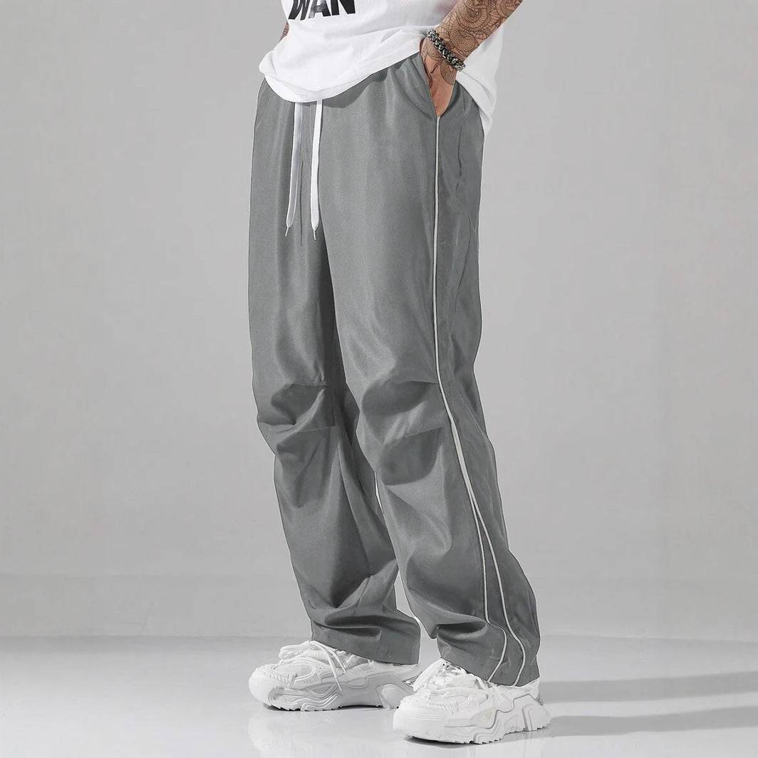 Mens striped track pants, gray, loose fit with side drawstring and vertical piping.