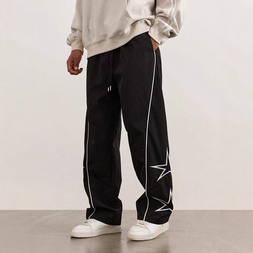 Black wide-leg trousers with white piping and star embroidery details on the side