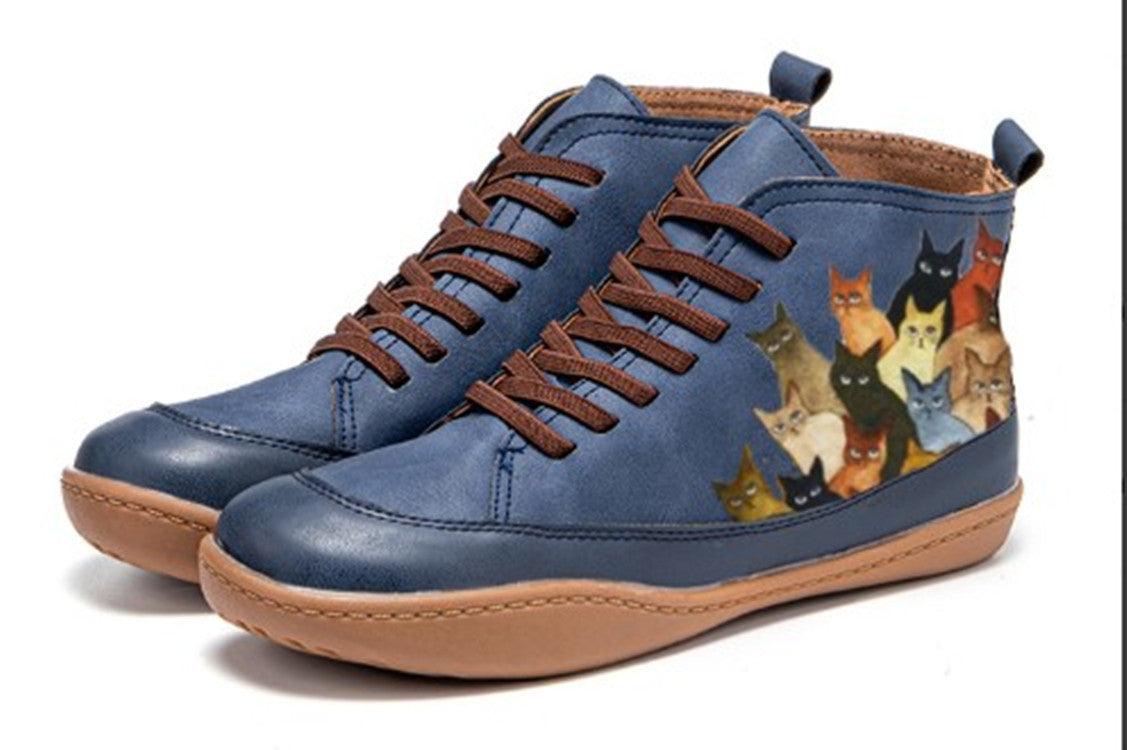 Blue pair of lace-up low-top sneakers with round toe, brown laces, and cat print sides