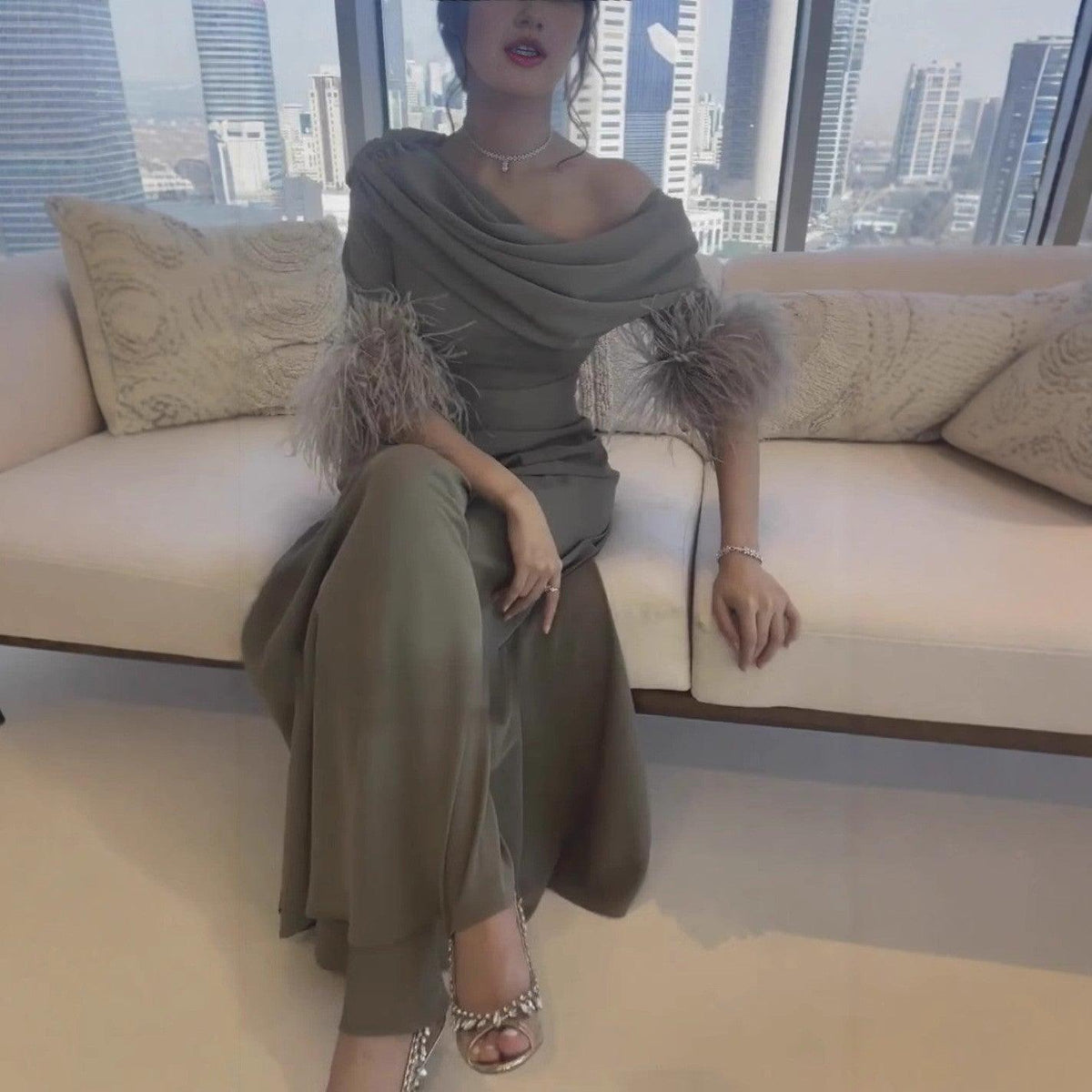 Women's olive green wide-leg jumpsuit with off-shoulder drape and gray feather cuffs