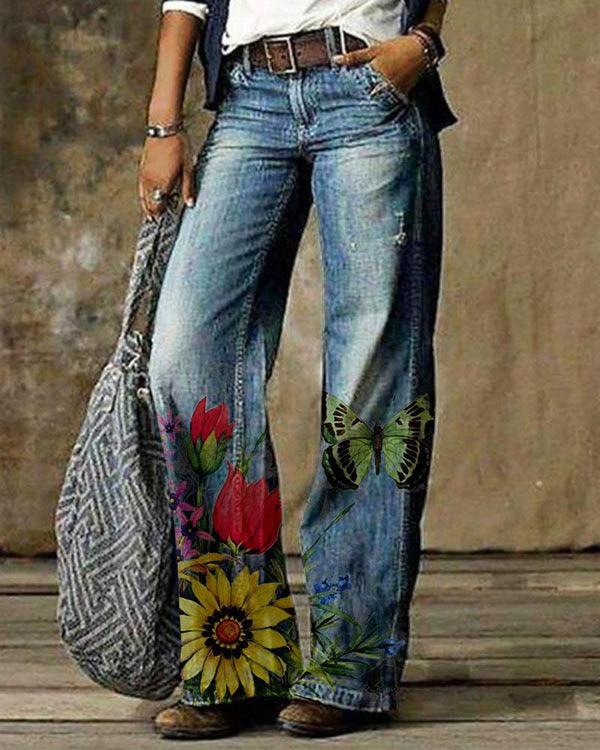 Light blue denim jeans with colorful floral and butterfly graphics on the lower legs