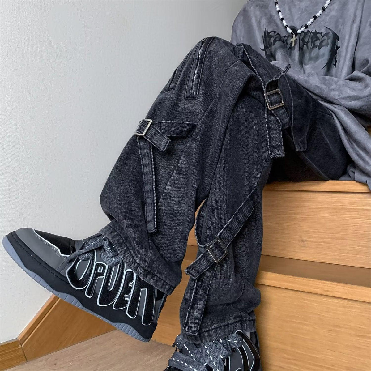 Men's black denim jeans close-up: cargo pockets and buckled strap details