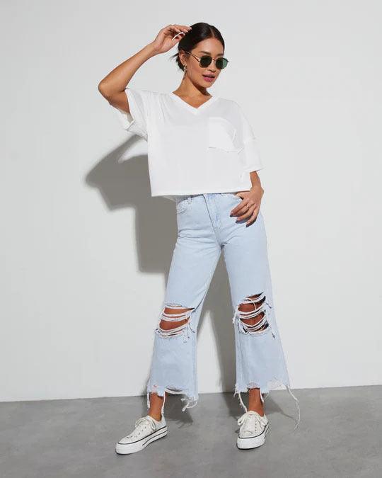 Light blue wide-leg ripped jeans with frayed cuffs, worn with casual white sneakers