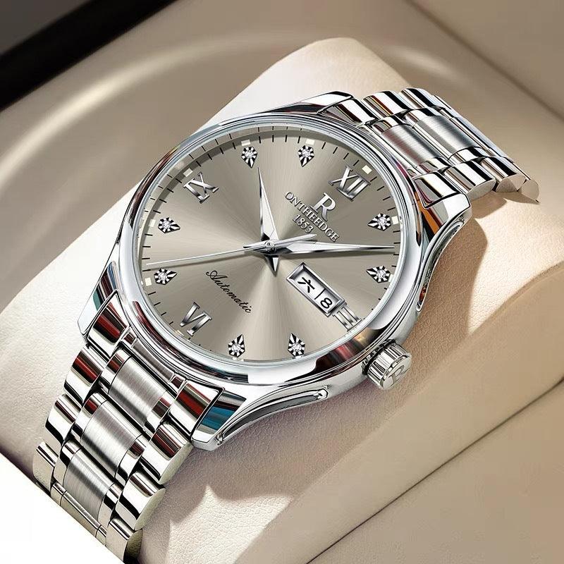 Silver metal mechanical watch with white dial and bracelet, date window at 3 o'clock
